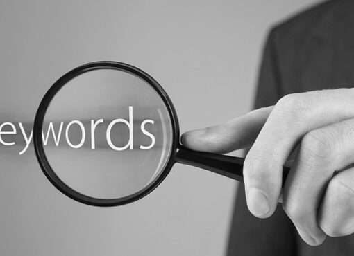 Man sucht mit Lupe das Wort Keywords - bildlich für Kanzleimarketing und Suchmaschinenoptimierung